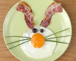 Osterfrühstück: Ein Hasengesicht mit Bacon und Ei auf einem grünen Teller.