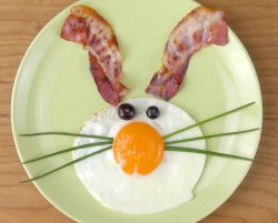 Osterfrühstück: Ein Hasengesicht mit Bacon und Ei auf einem grünen Teller.
