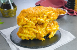 Ein paniertes Mac-and-Cheese-Pasta-Sandwich auf einer runden Schiefertafel.