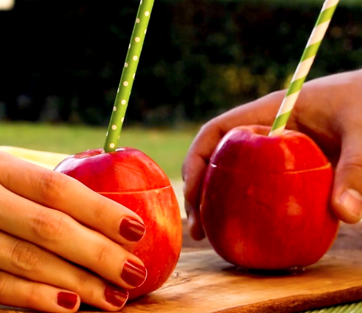 2 Hände greifen je einen Big Apple Cocktail im Apfel
