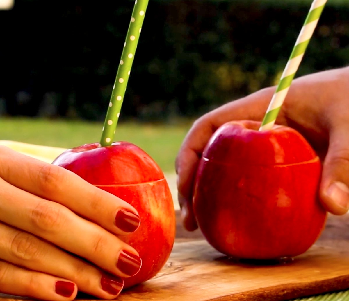 2 HÃ¤nde greifen je einen Big Apple Cocktail im Apfel