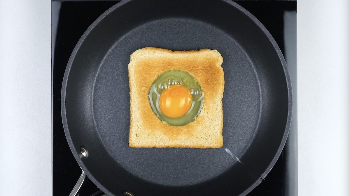 In ausgestochenen Kreis in Toast in Pfanne wird ein Ei gefÃ¼llt