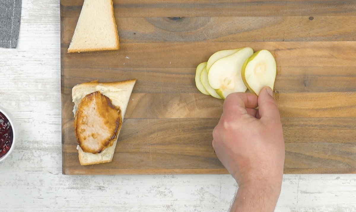 Eine Birnenscheibe wird auf das Schweinefleisch gelegt