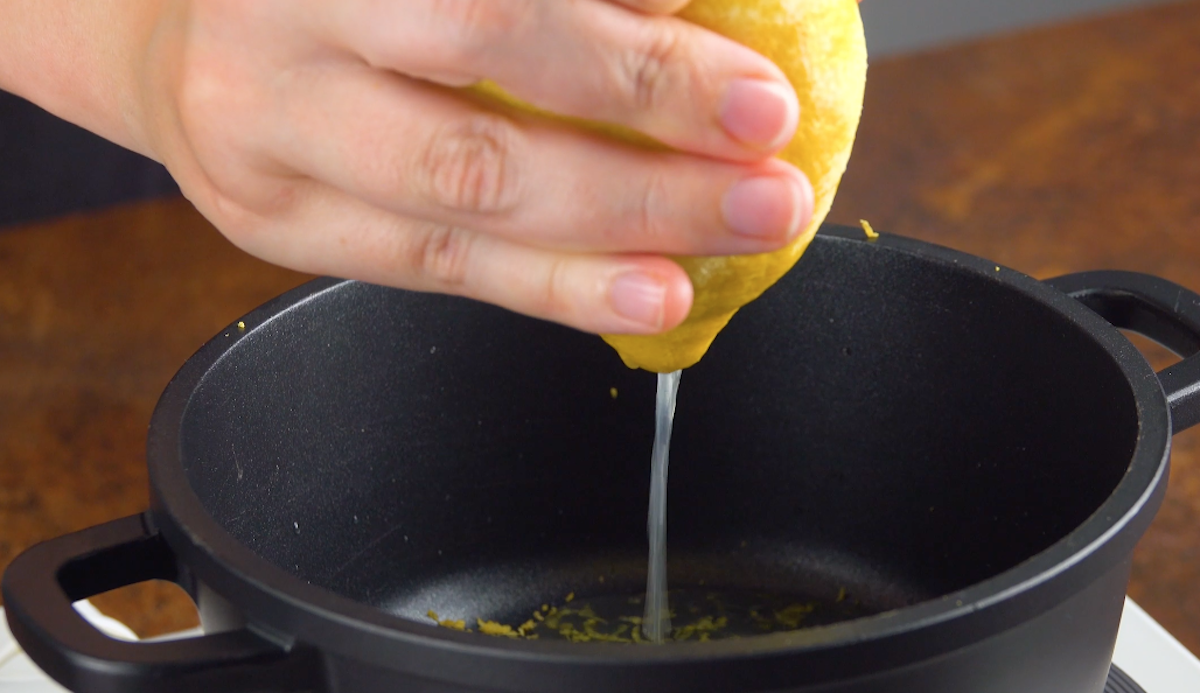 Eine Zitrone wird in Topf ausgepresst