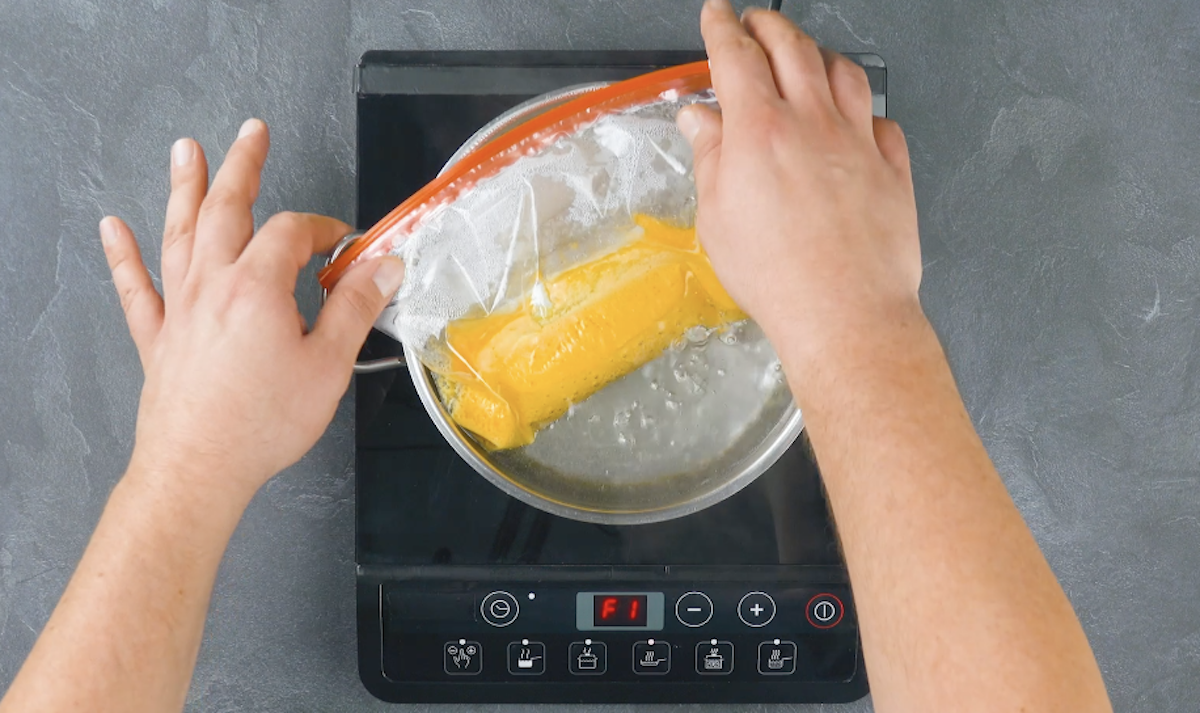 Ein Plastikbeutel, gefÃ¼llt mit Eigelb, wird in einen Topf mit kochendem Wasser gelegt.