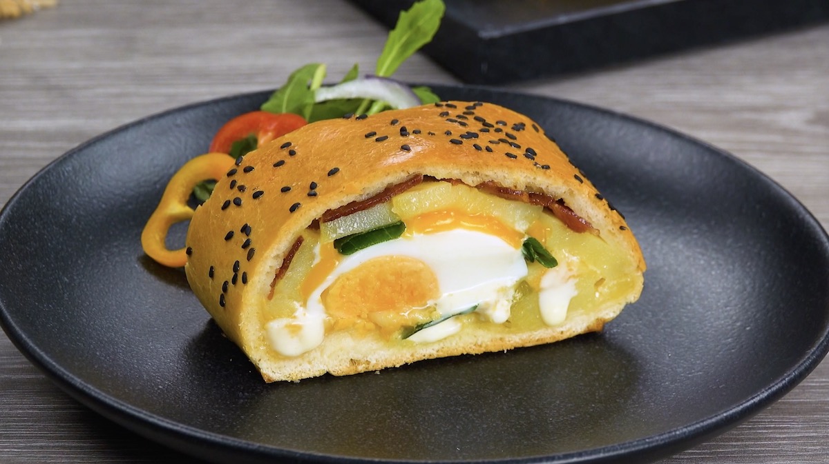 Ein StÃ¼ck BauernfrÃ¼hstÃ¼ck-Calzone auf schwarzem Teller