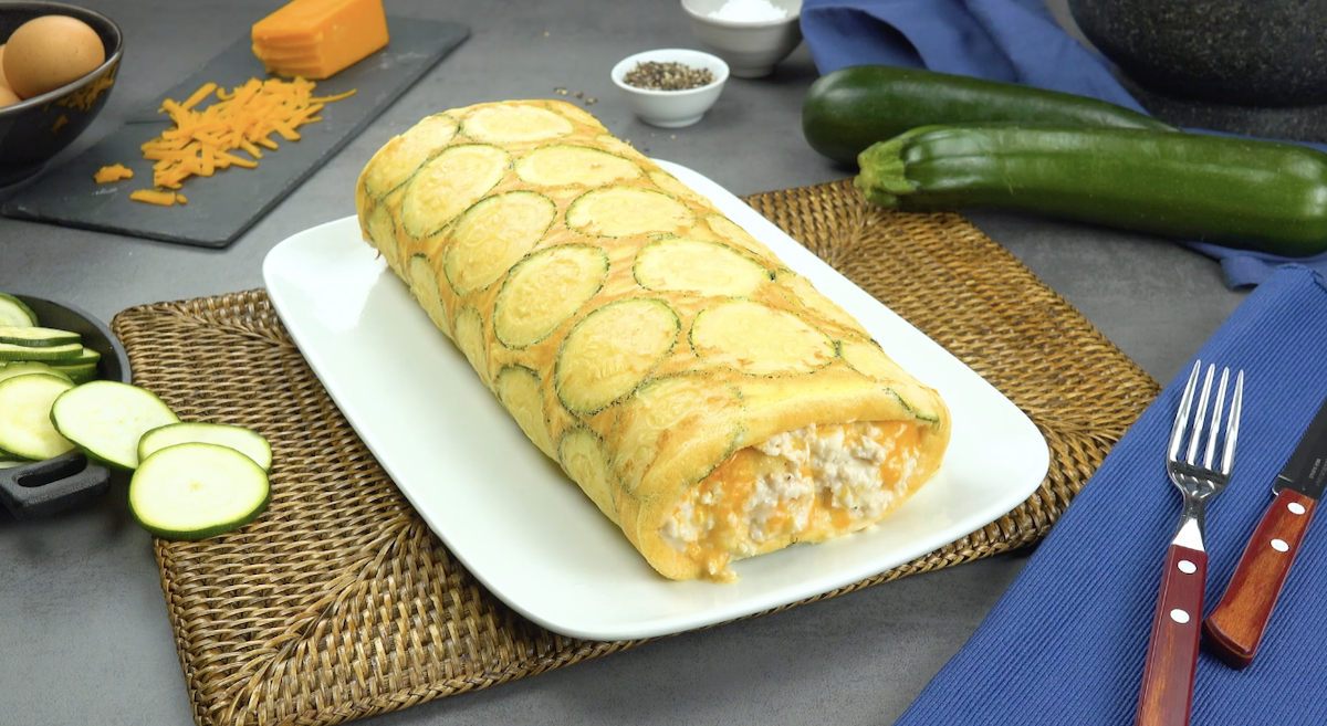 Zucchini-Omelett-Rolle mit FÃ¼llung aus Cheddar und HÃ¤hnchen auf weiÃŸem Teller