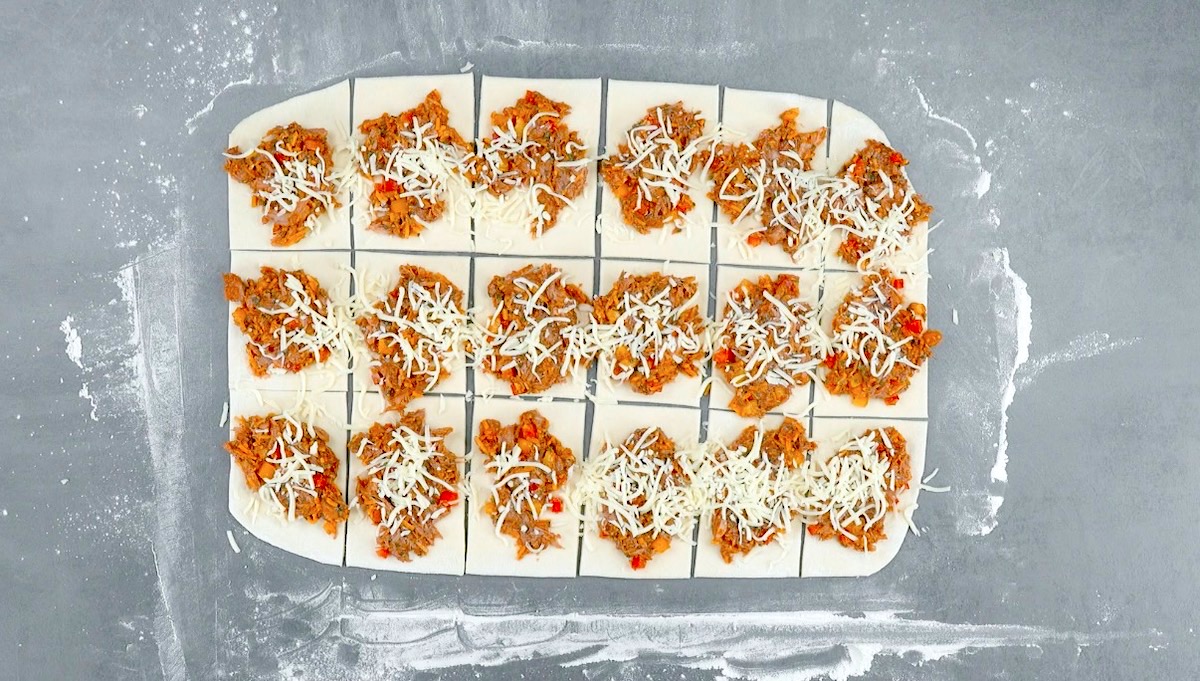 Rechtecke aus Pizzateig werden mit Pulled Pork und Käse belegt