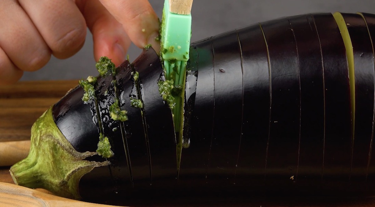 Die Einschnitte in der Aubergine werden mit grünem pesto gefüllt.