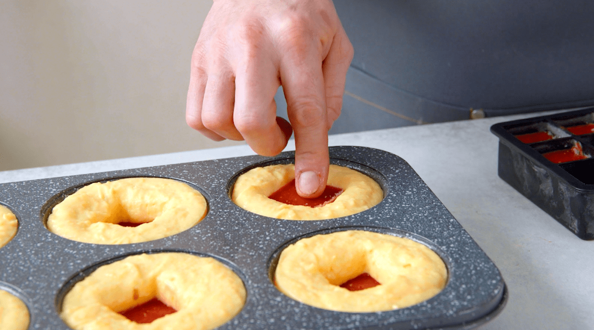 Gefrorene Erdbeerkompott-WÃ¼rfel werden in eine Muffinform gegeben.