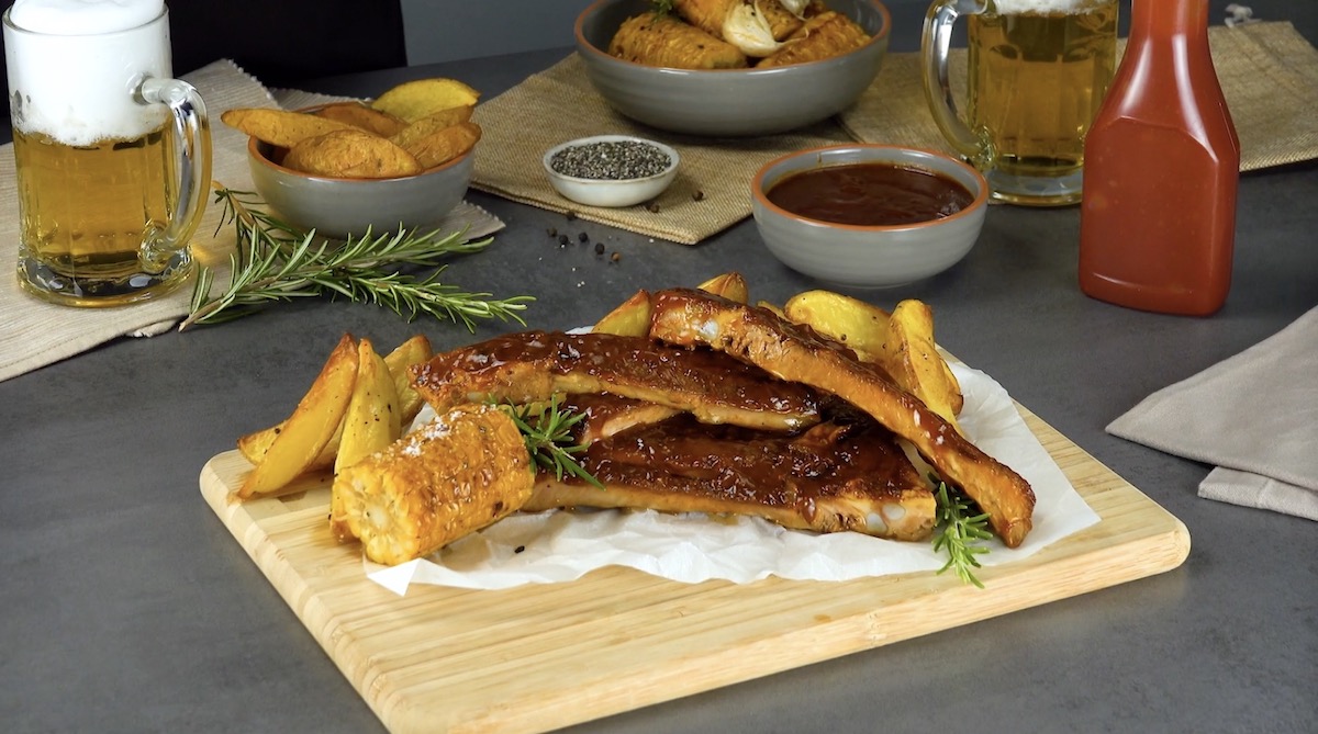 Spareribs mit gegrilltem Mais und Kartoffel-Wedges auf Holzbrett