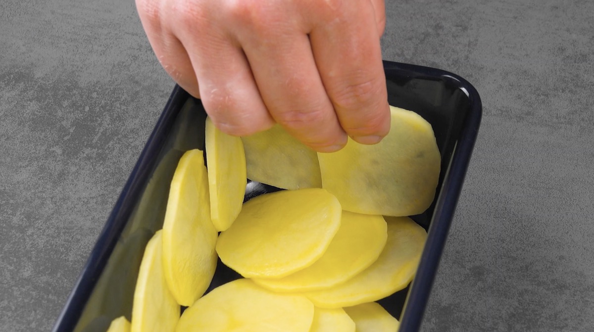 Boden und Seiten einer Kastenform werden mit Kartoffelscheiben ausgelegt