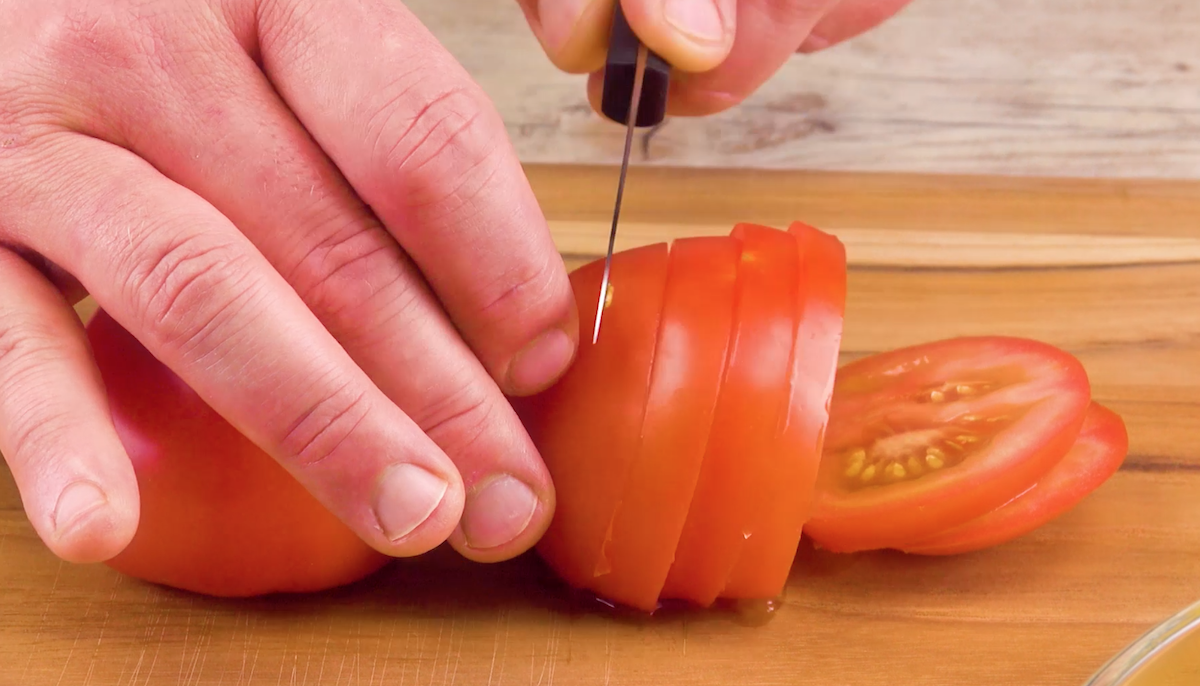 Eine Tomate wird in Scheiben geschnitten