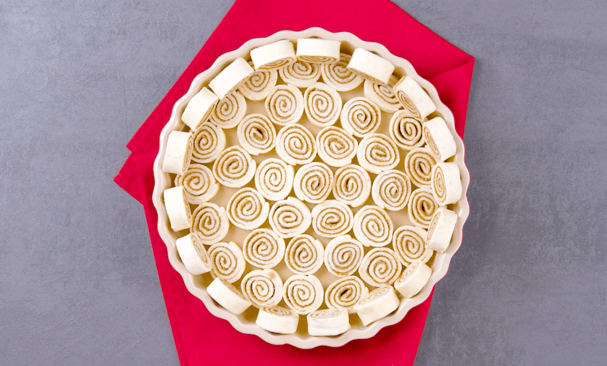 Eine Kuchenform wurde mit zahlreichen Zimtschnecken ausgelegt