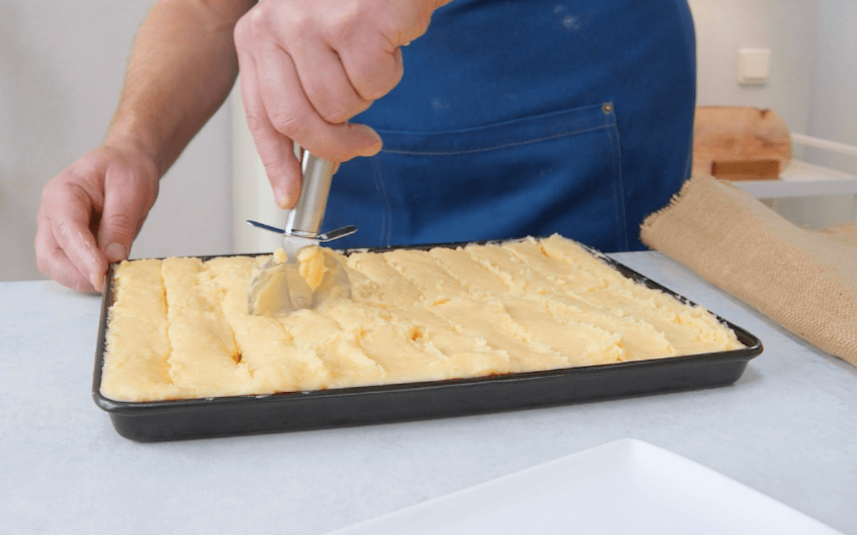 Mit Cheddar gefÃ¼llte KartoffelpÃ¼ree Platte wird mit einem Pizzaschneider in Streifen geschnitten