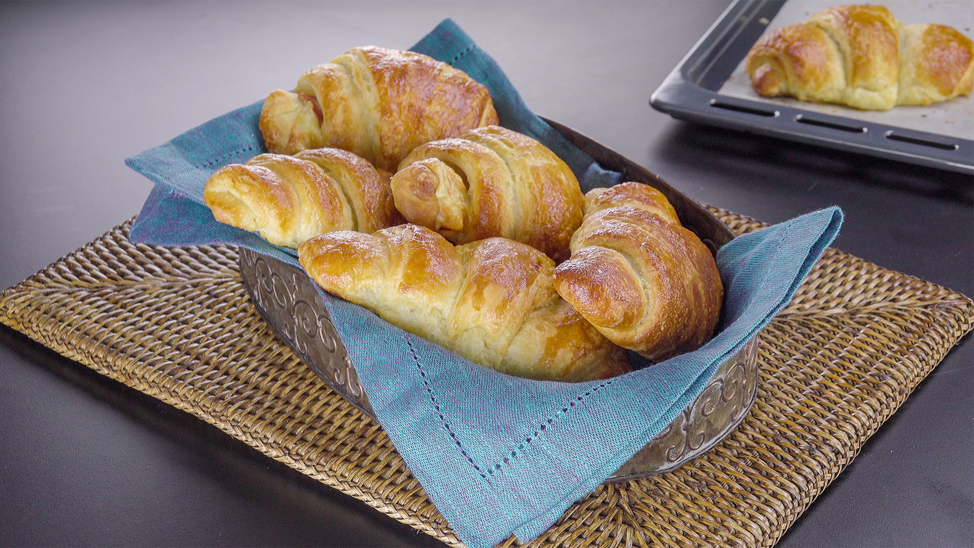 Croissants in einem mit einem Geschirrtuch ausgelegten Brotkorb.