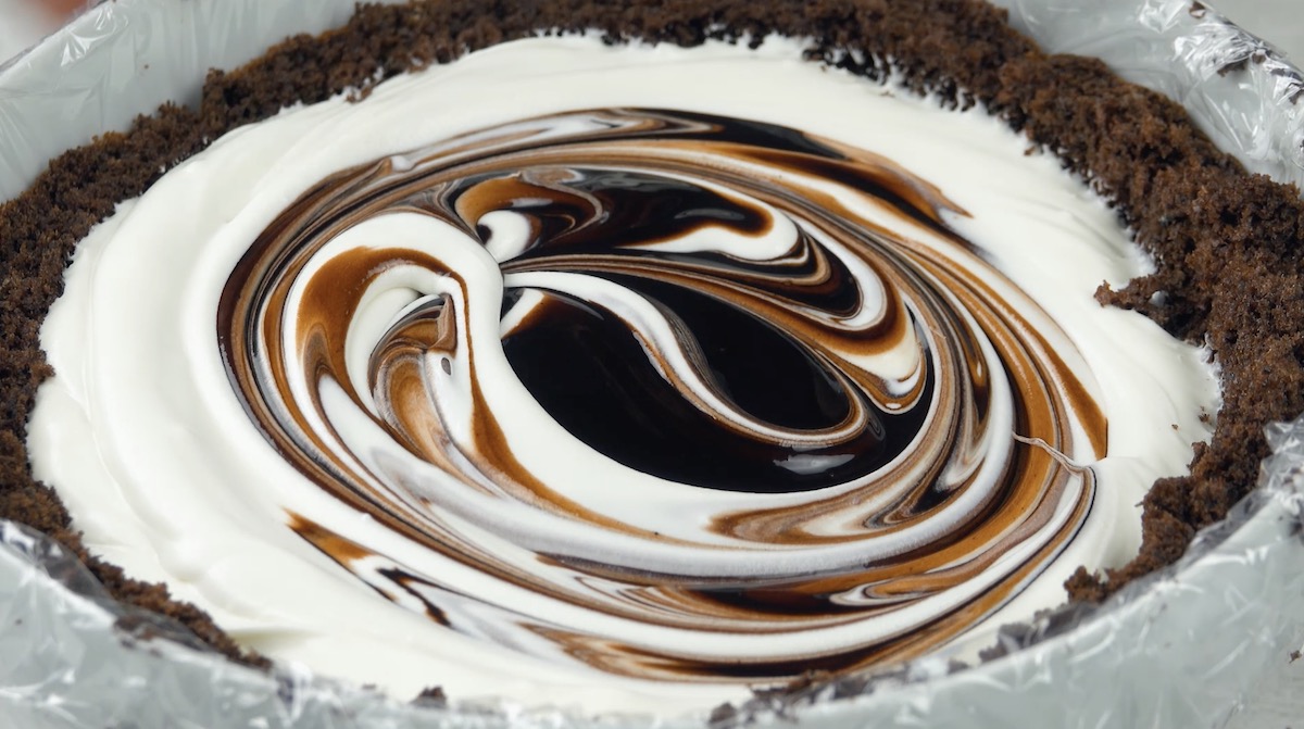 SchokoladensoÃŸe wird zur weiÃŸen Schokoladencreme hinzugefÃ¼gt und zu einem Strudel verrÃ¼hrt.