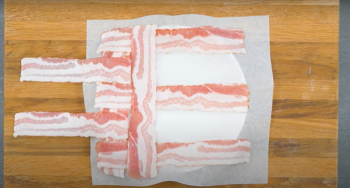 Baconstreifen werden auf Backpapier miteinander verflochten