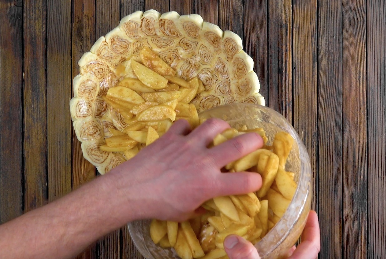 Marinierte ApfelstÃ¼cke werden in eine Kuchenform mit Zimntschnecken gegeben