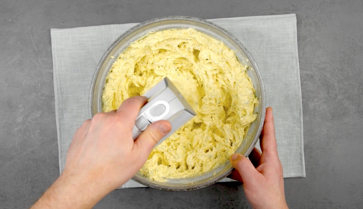 Kräuterbutter wird mit Handrührgerät schaumig geschlagen