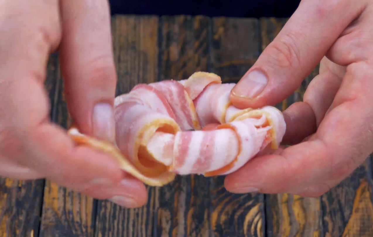 Zwiebelringe werden mit Baconscheiben umwickelt