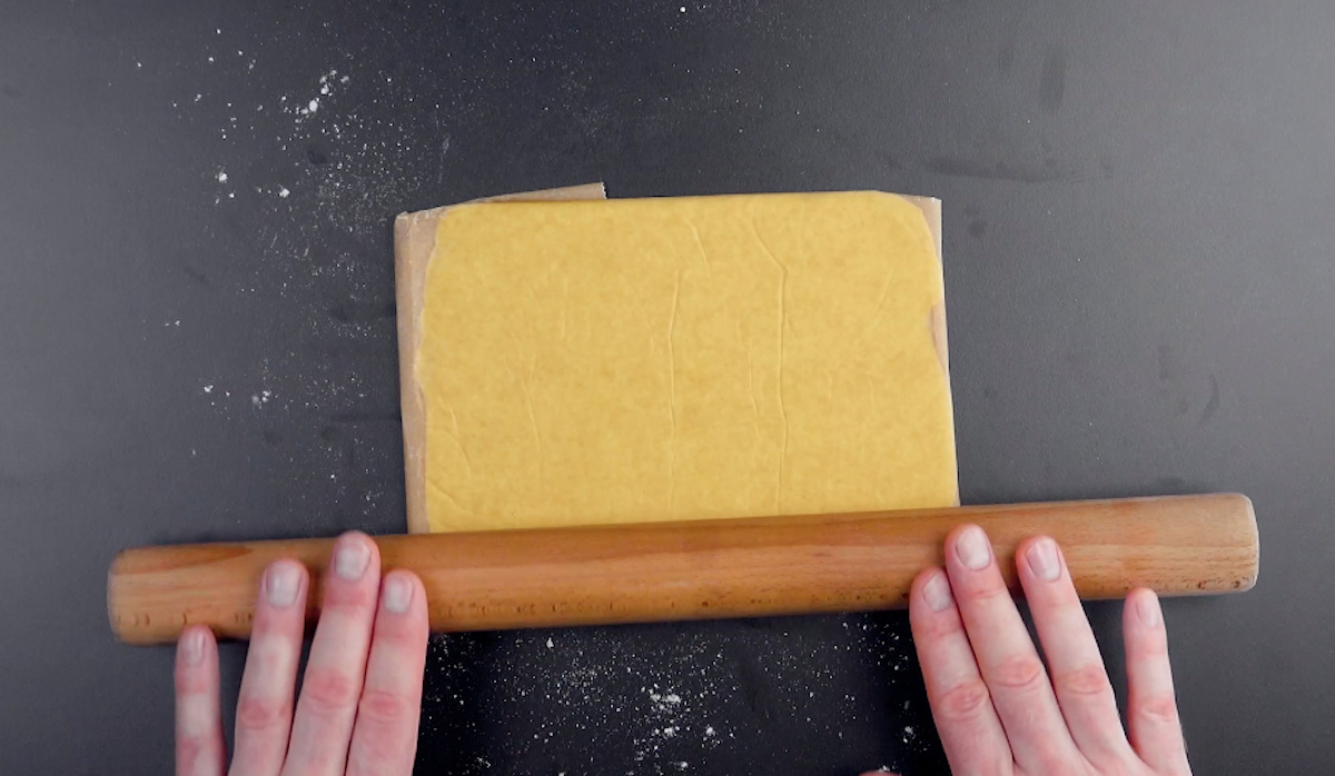 Ein StÃ¼ck kalte Butter wird in Backpapier gewickelt und zu einem Rechteck ausgerollt