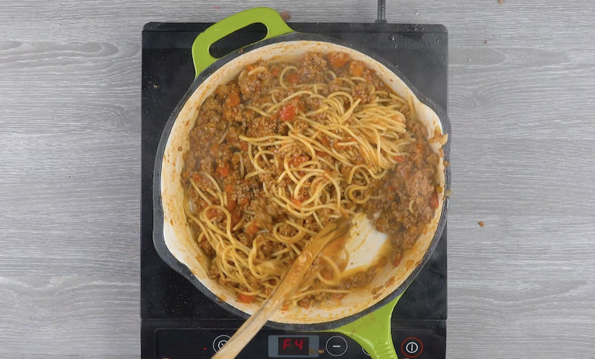 Spaghetti werden zu Hackfleisch und Pizzatomaten in Pfanne hinzugefÃ¼gt