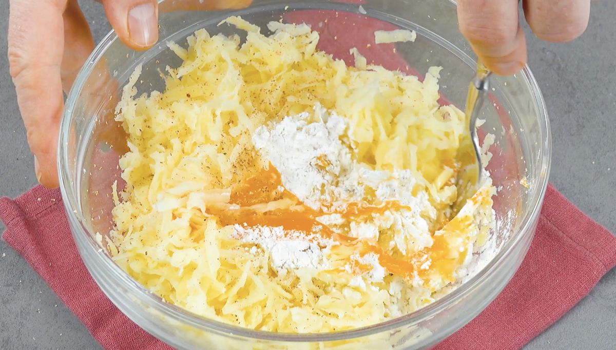 Geriebene Kartoffeln werden mit Eigelb, Stärke und Gewürzen in Schüssel vermengt