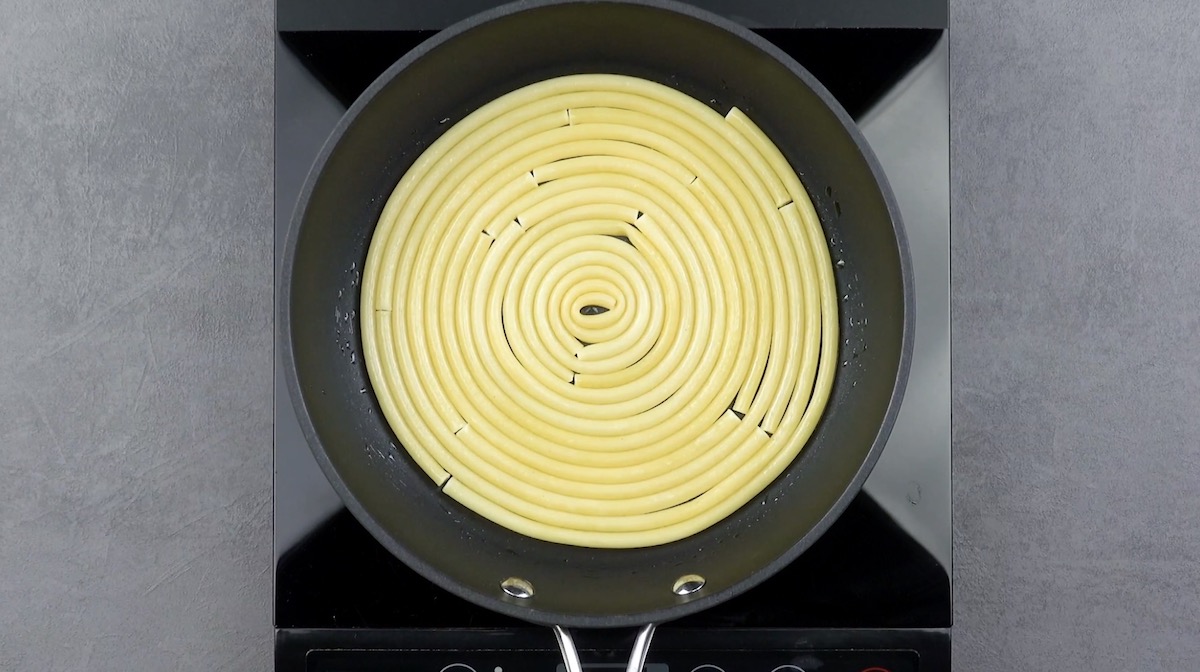 Al dente gekochte Nudeln werden spiralförmig in Pfanne gelegt