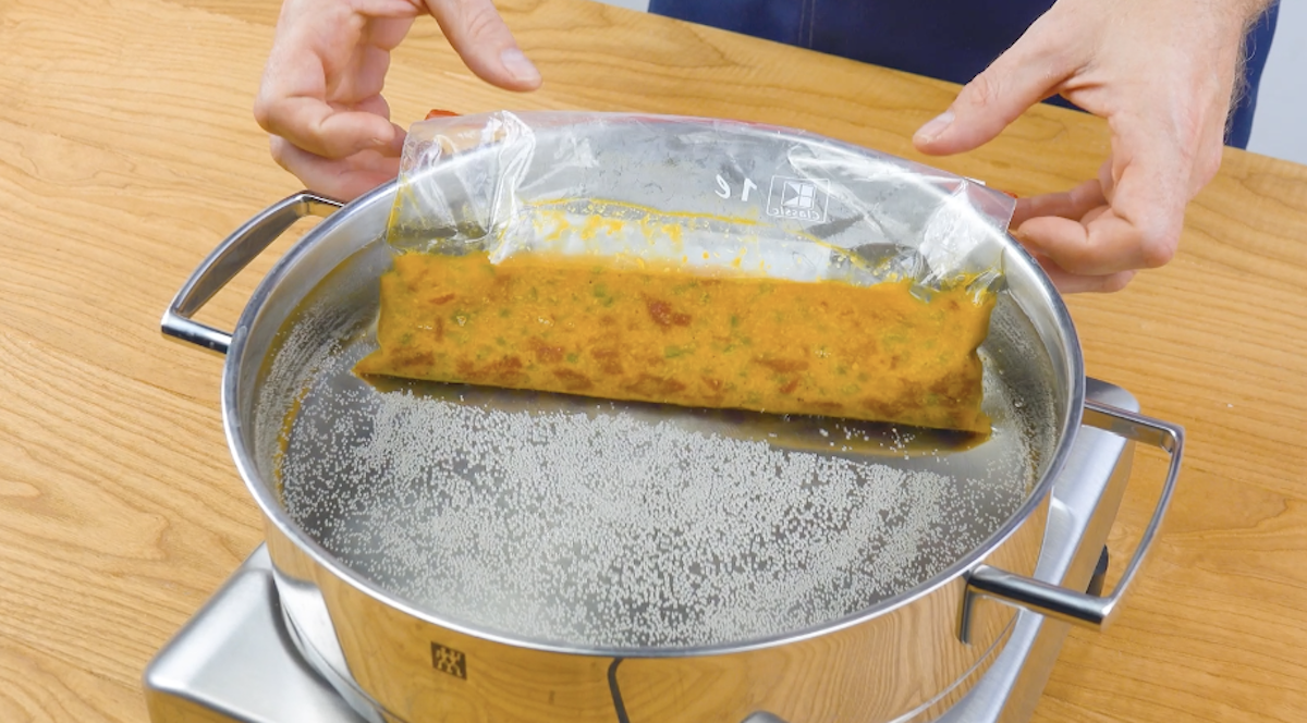 Cheddar, Eigelbe und Paprika- und Salamistücke werden in Ziplock-Beutel gefüllt und in warmem Wasser gegart