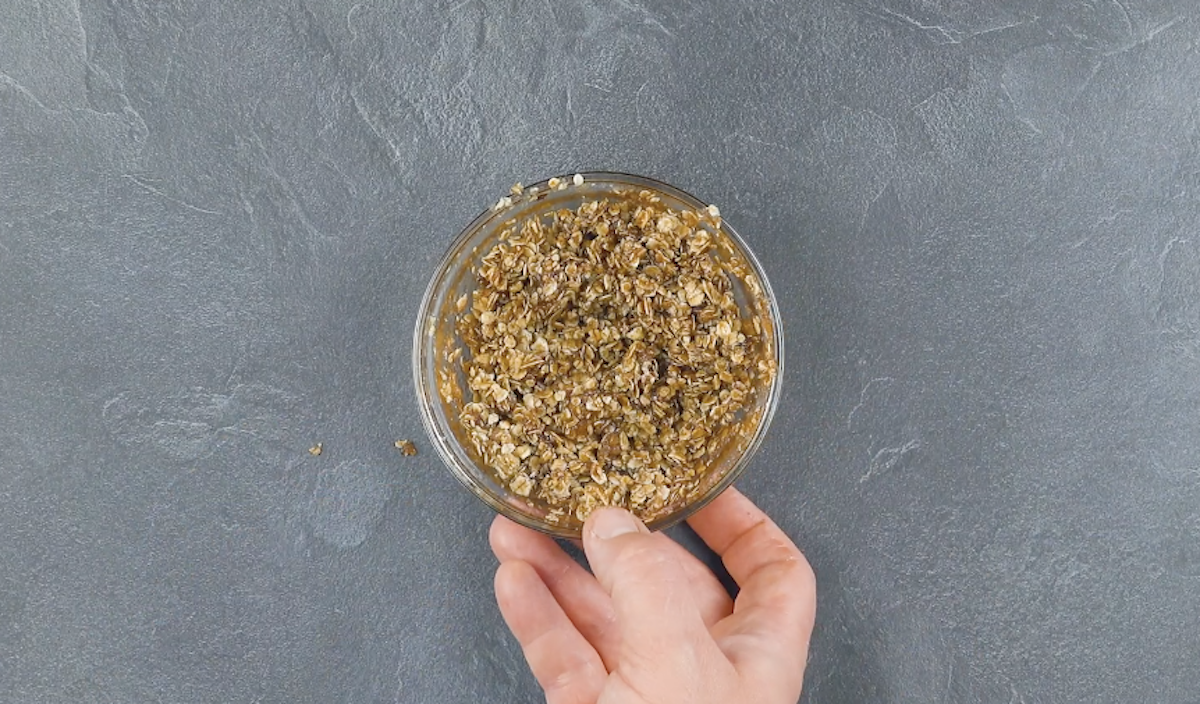 Geschmolzene Butter wird mit Zucker und Haferflocken in Schale vermengt