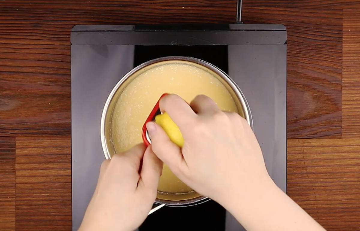 Zitronenschale wird mit Reibe in Puddingcreme gerieben