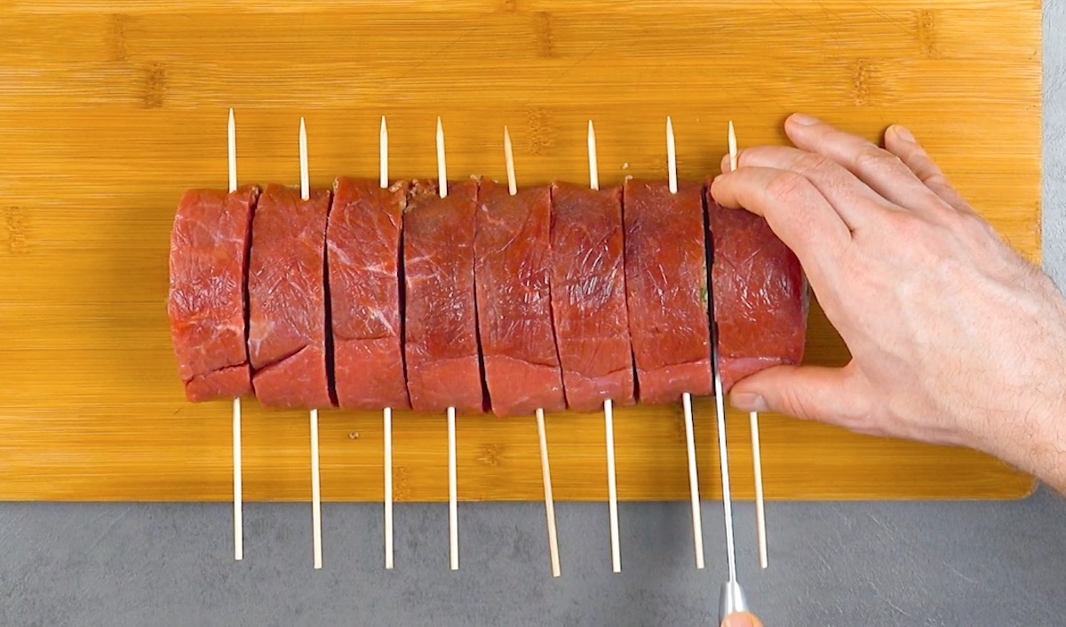 Rinderroulade mit Holspießen wird in Stücke geschnitten