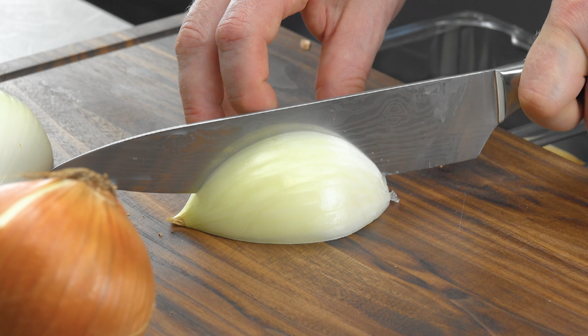 Halbierte Zwiebel wird mit Messer eingeschnittem