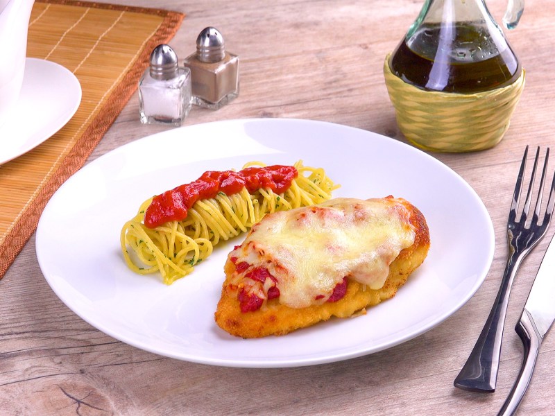 Parmesan-Hähnchen mit Nudeln und Tomatensoße auf einem Teller.