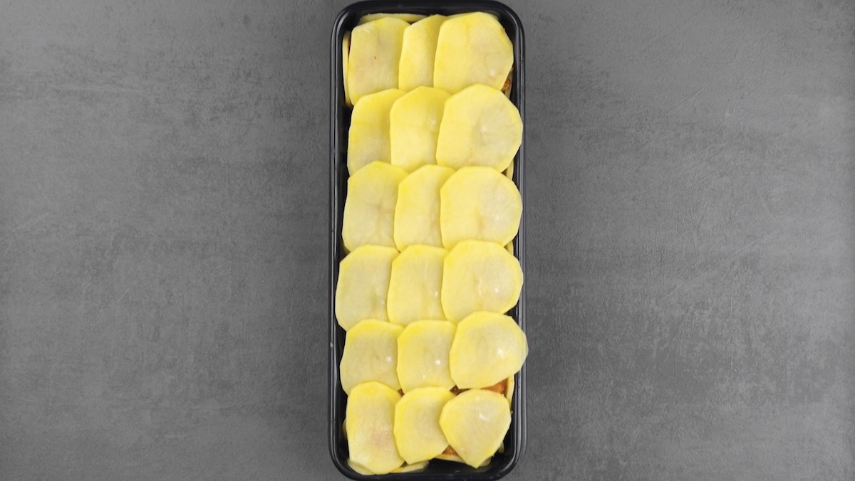Kartoffelauflauf in Kastenform wird mit Kartoffelscheiben abgedeckt