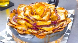 Eine Kartoffelrose, gefüllt mit Brie, Bacon und Zwiebeln in einer Pfanne.