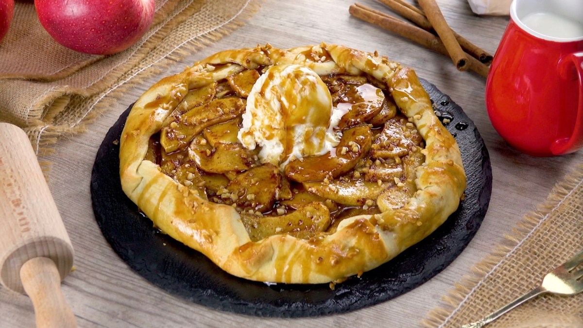 Apfel-Karamell-Dessert auf einem Teller. Ein Nudelholz liegt als Dekoration daneben.