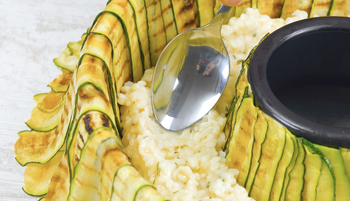 Risotto wird in Kuchenform auf Zucchinischeiben verteilt