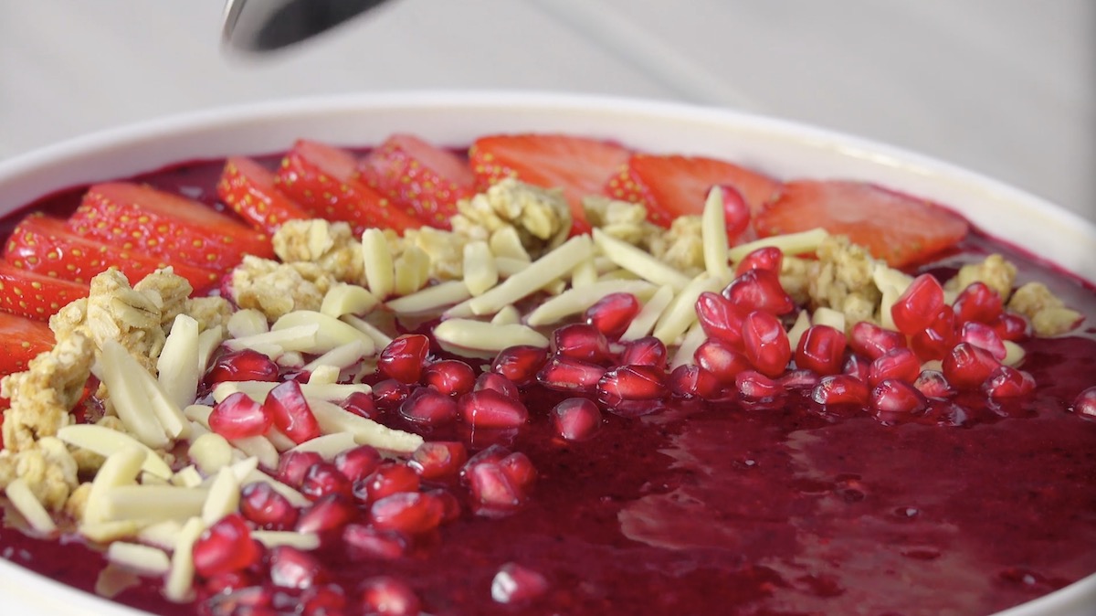 Smoothie-Bowl mit Erdbeeren, Mandelstiften, Granatapfelkernen und MÃ¼sli