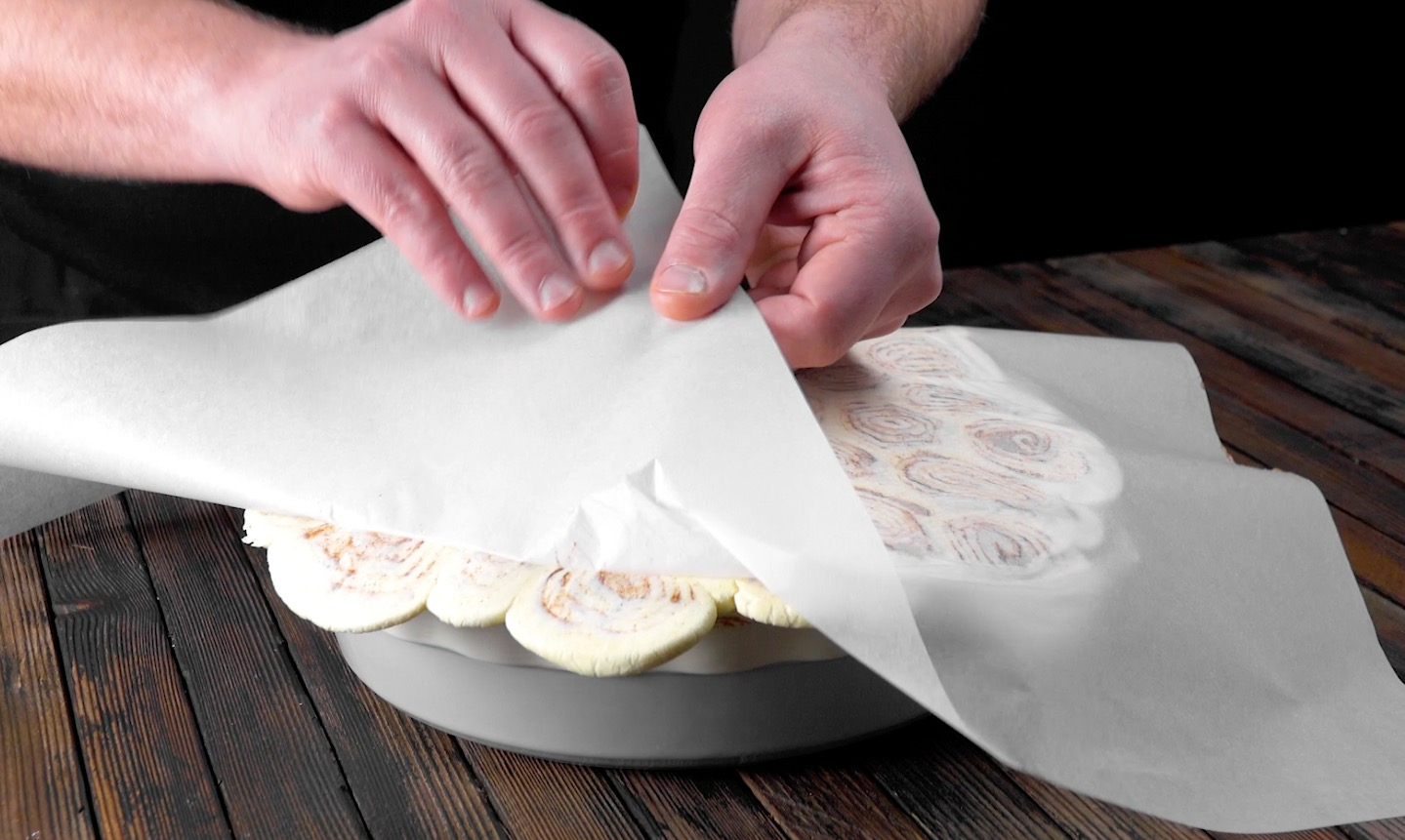 Backpapier wirf von plattgerollten Zimtschnecken entfernt