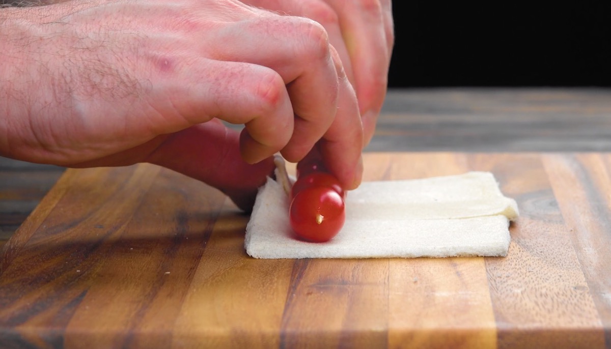 Tomaten am SpieÃŸ werden in Toastbrotscheiben eingerollt