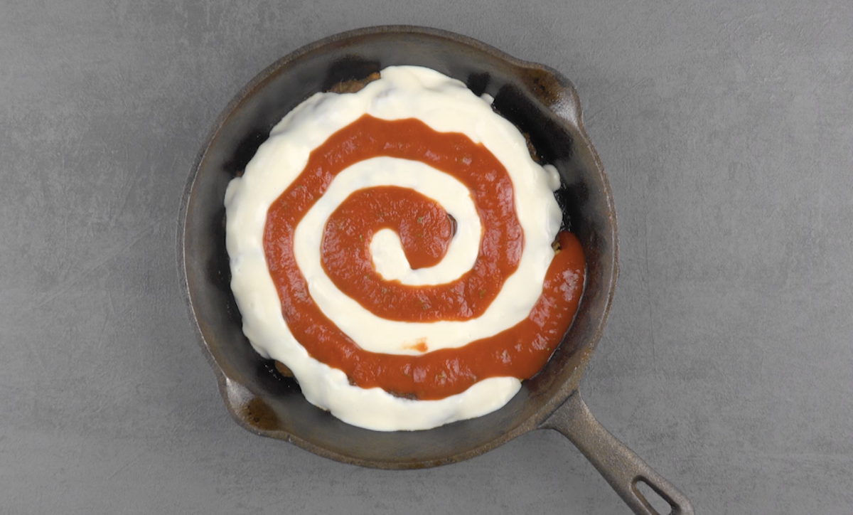 Béchamel- und Tomatensoße werden spiralförmig in Pfanne geossen