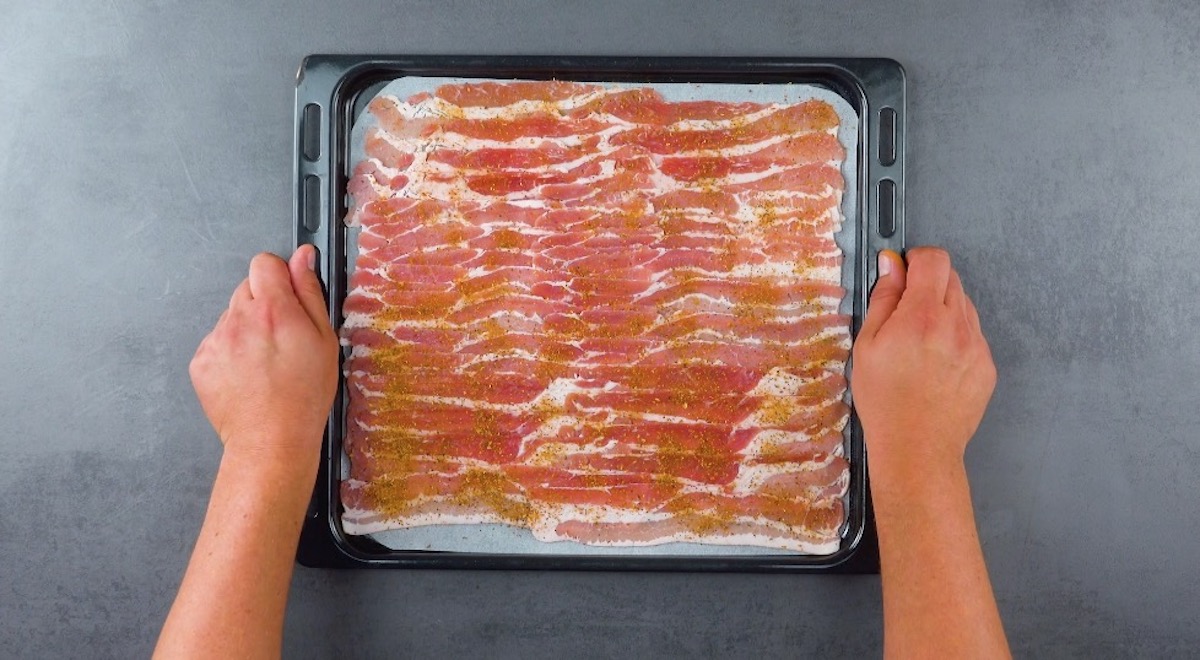 Baconscheiben werden auf ein mit Backpapier ausgelegtem Backblech verteilt und mit BBQ-GewÃ¼rz betreut