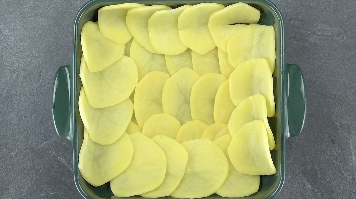 Kartoffelscheiben werden in Auflaufform gelegt