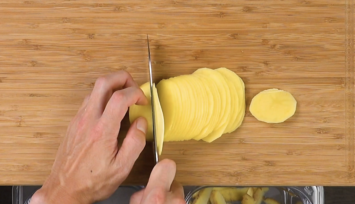 Eine rohe Kartoffel wird in dÃ¼nne Scheiben geschnitten