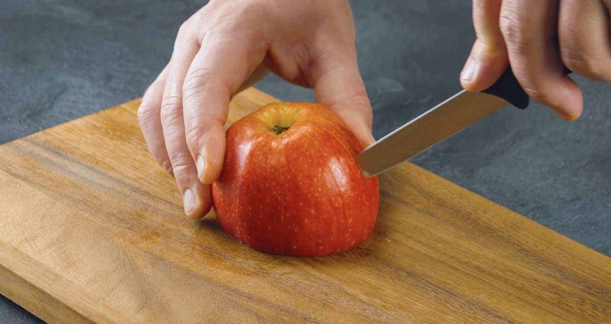 Der Apfel wird auf die Schnittstelle gestellt und auch seine Schale rundherum leicht eingeschnitten