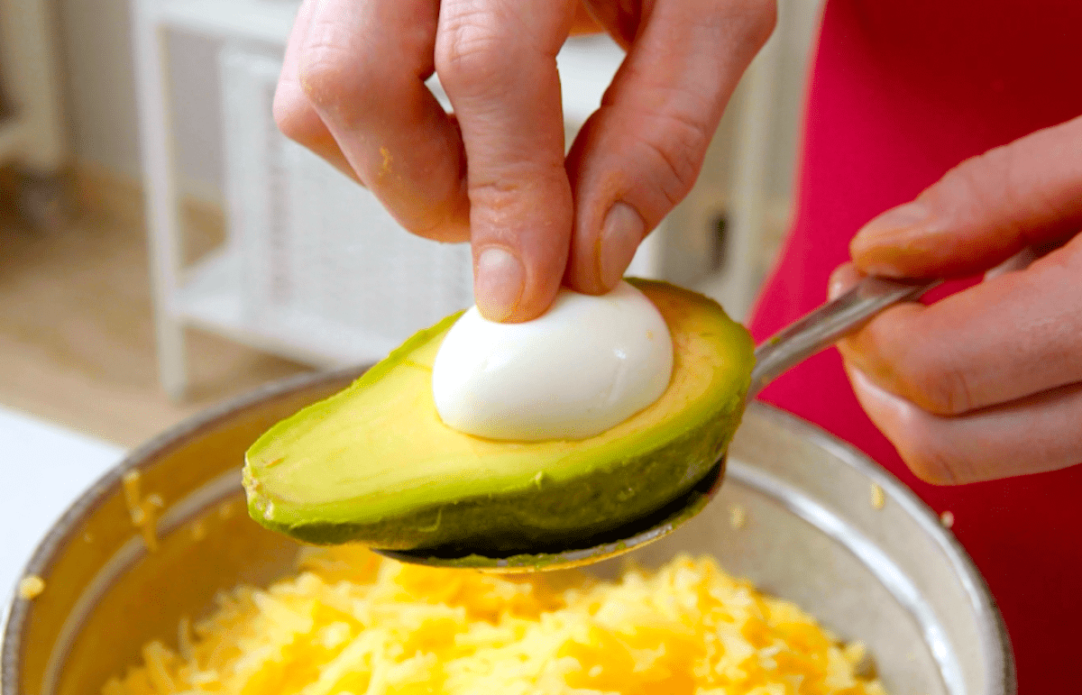 Ein gekochtes Ei wird auf eine AvocadohÃ¤lfte gelegt, und zwar in die Mulde, in der sich zuvor der Kern befand.