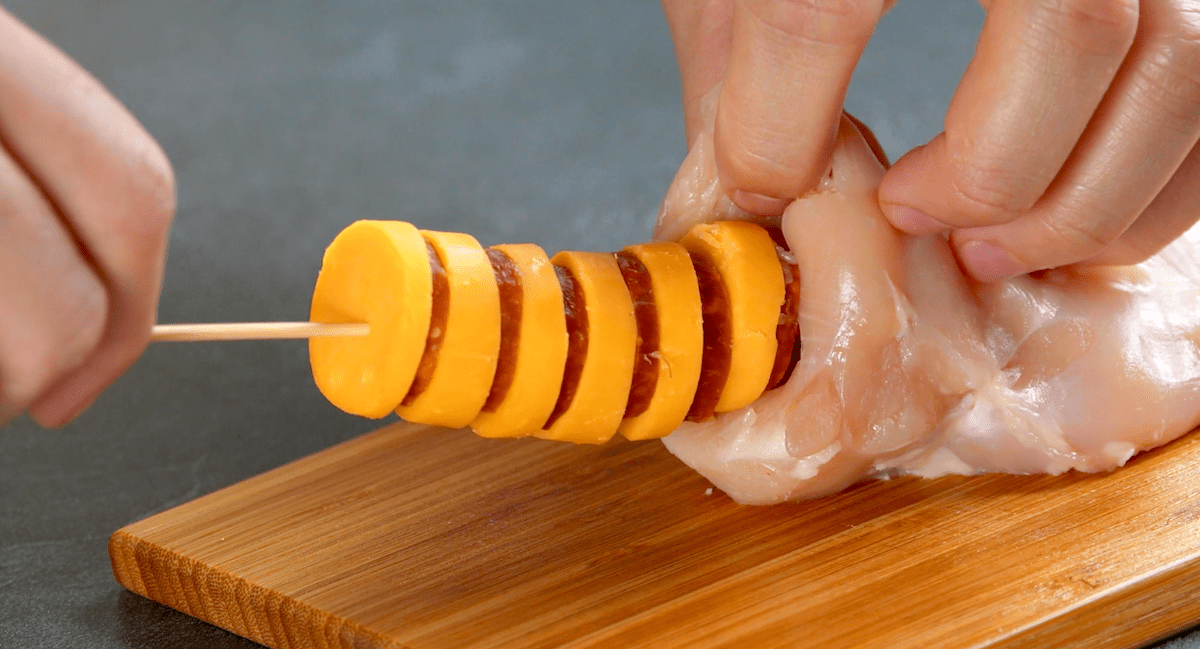 Cheddar und Chorizo in Scheiben werden mithilfe eines HolzspieÃŸes in die HÃ¤hnchenbrust eingefÃ¼hrt