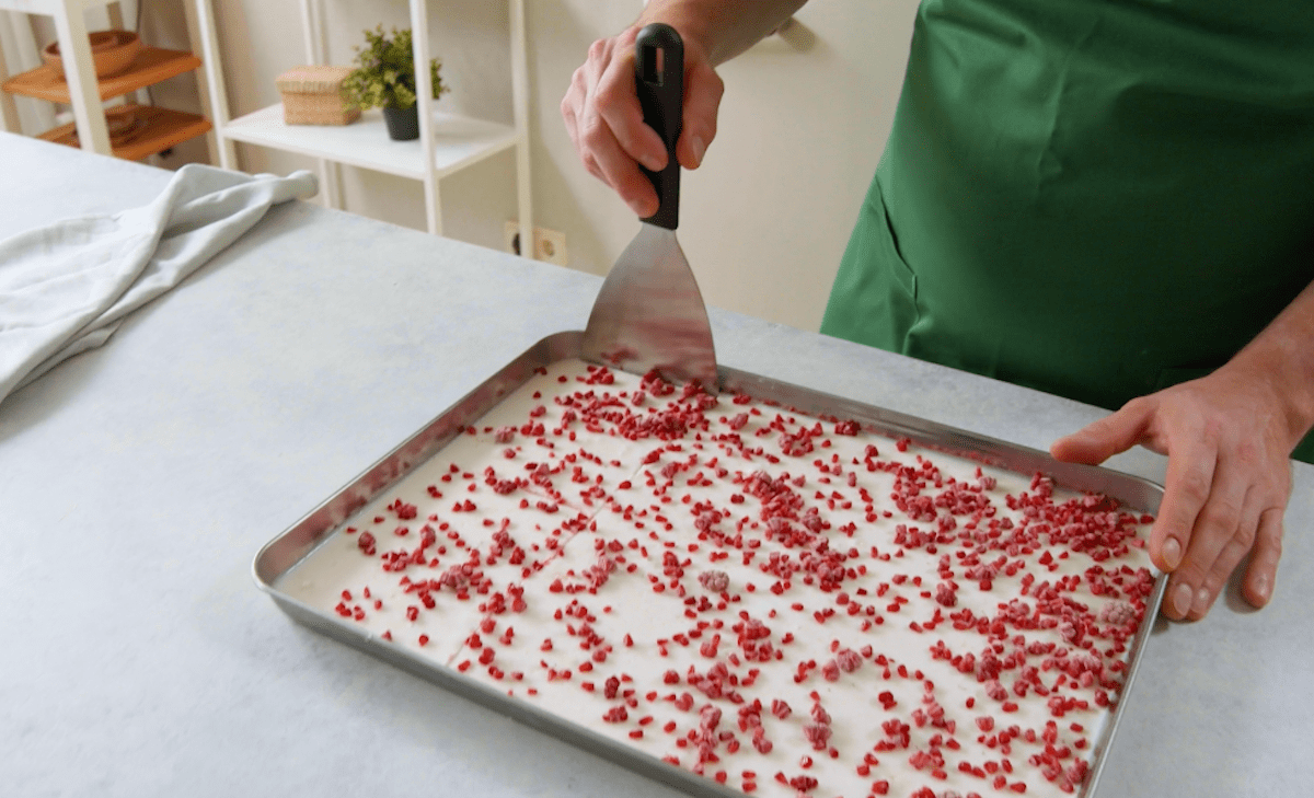 Fest gewordener Kokospudding mit Himbeer-Raspeln wird in Teile geschnitten